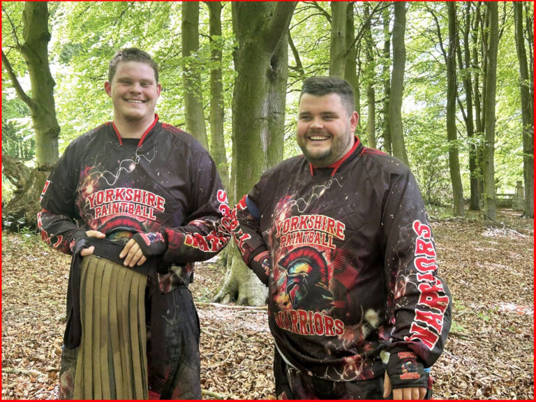 Two men in Yorkshire Paintball Warriors Padded jerseys smiling in a wooded forest setting